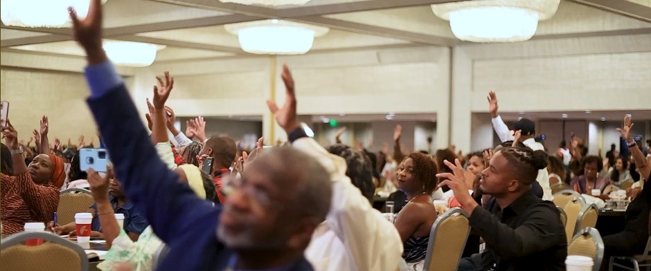 A packed Black Business School audience with hands raised